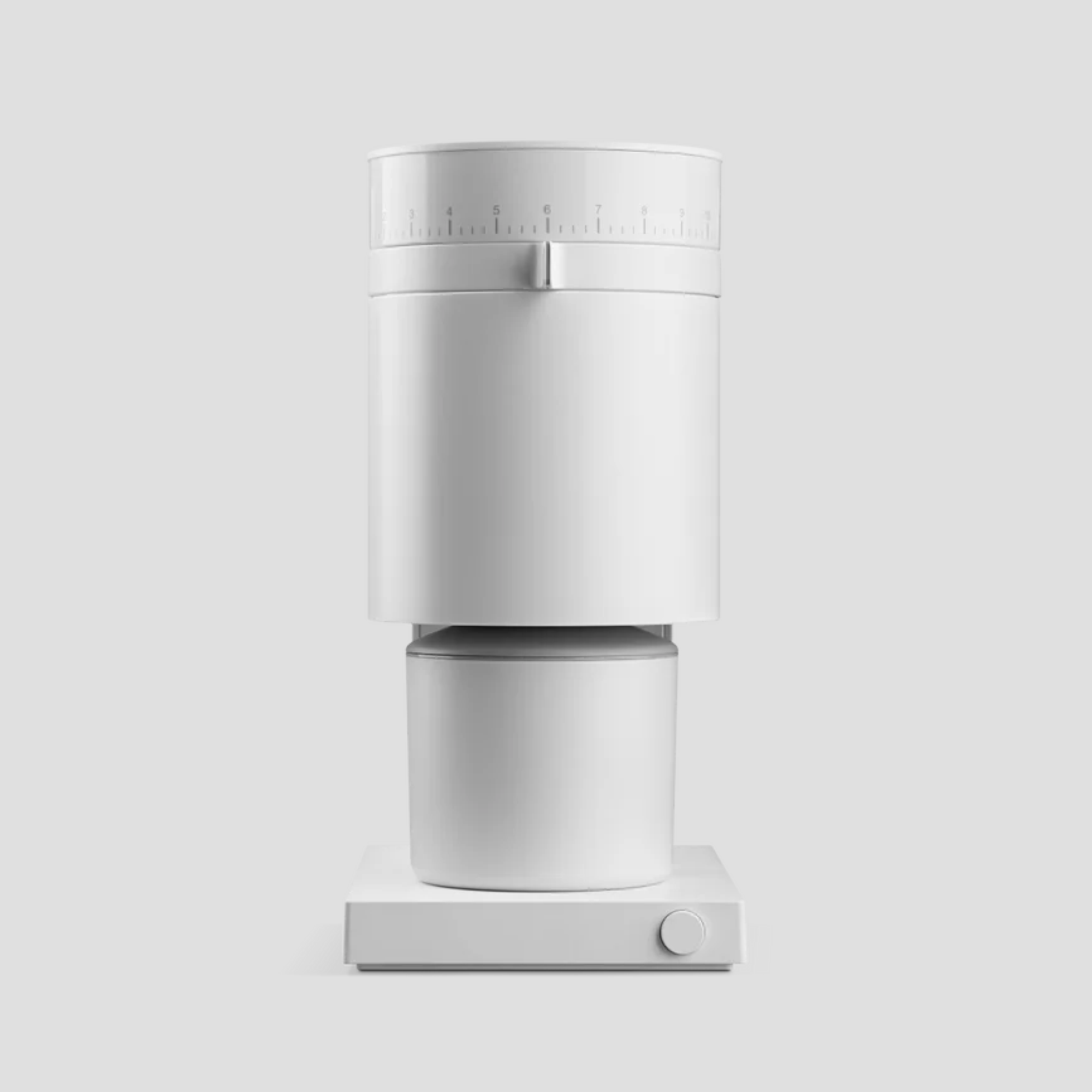 Molino de café eléctrico de diseño minimalista en color blanco. Cuenta con un selector de molienda numérico en la parte superior, con una palanca metálica como indicador. El cuerpo cilíndrico encaja sobre un recipiente recolector también blanco. La base cuadrada incluye un único botón giratorio en la esquina inferior derecha.
